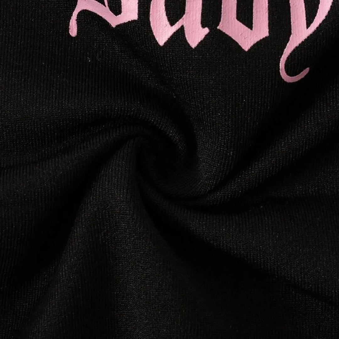 Close-up of black fabric with pink Baby script text from a cut-out bodysuit design.